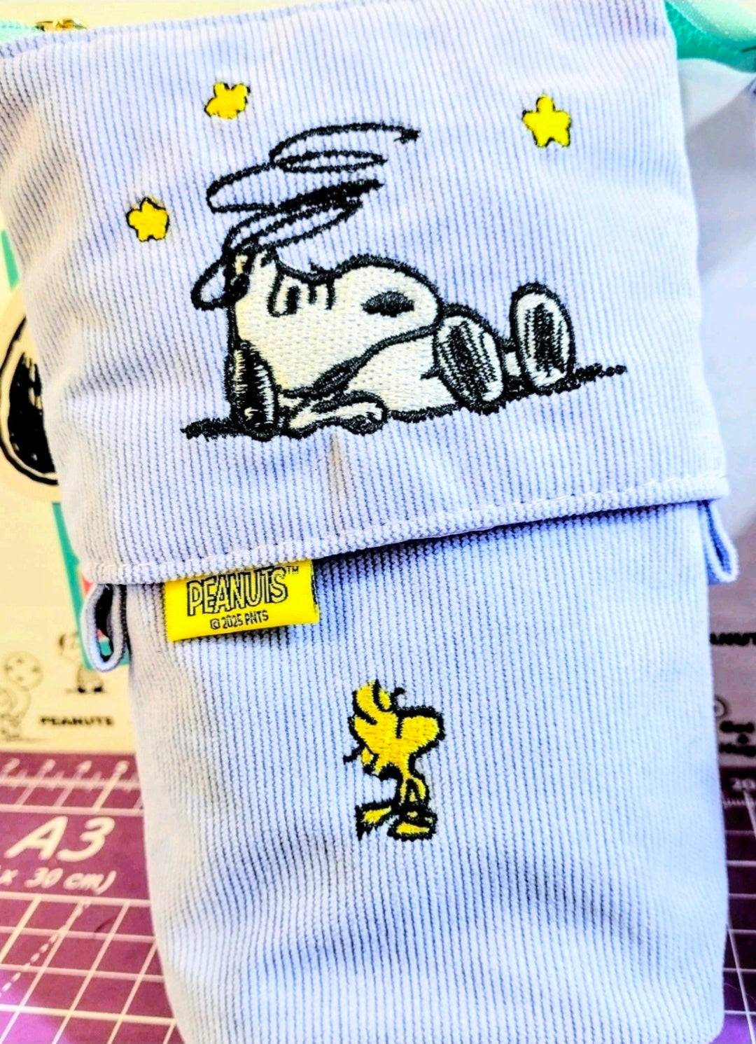 Lavender corduroy pop-up pencil case with Snoopy and star embroidery, standing.