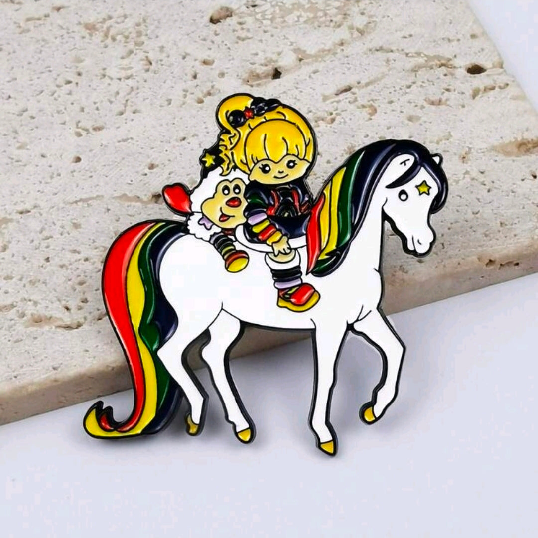 Enamel riding duo pin of a blond girl on a white horse with rainbow mane and stars