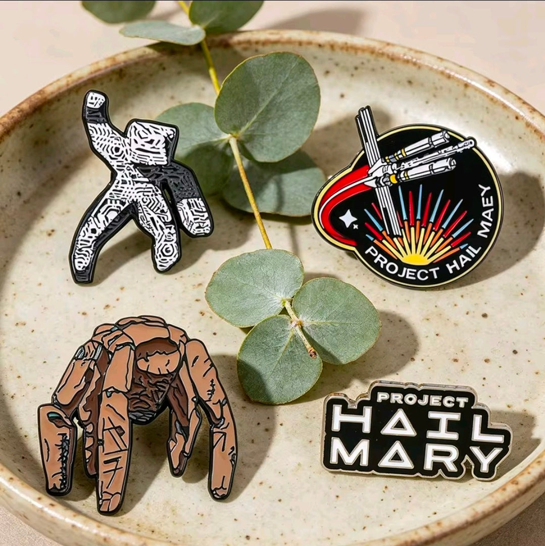 4-piece enamel pin set on a dish: character figures, text logo, and round ship emblem