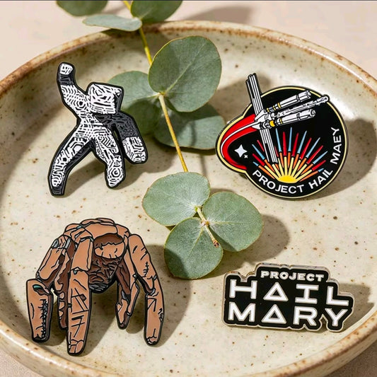 4-piece enamel pin set on a dish: character figures, text logo, and round ship emblem