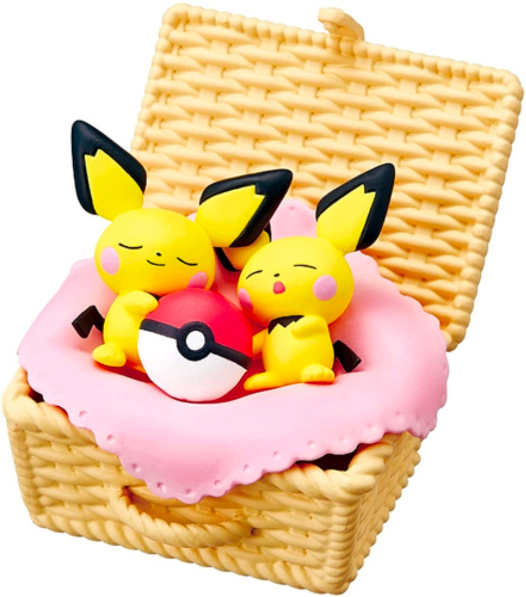 Miniature Pikachu and Pichu sleeping on a pink cushion inside a woven basket