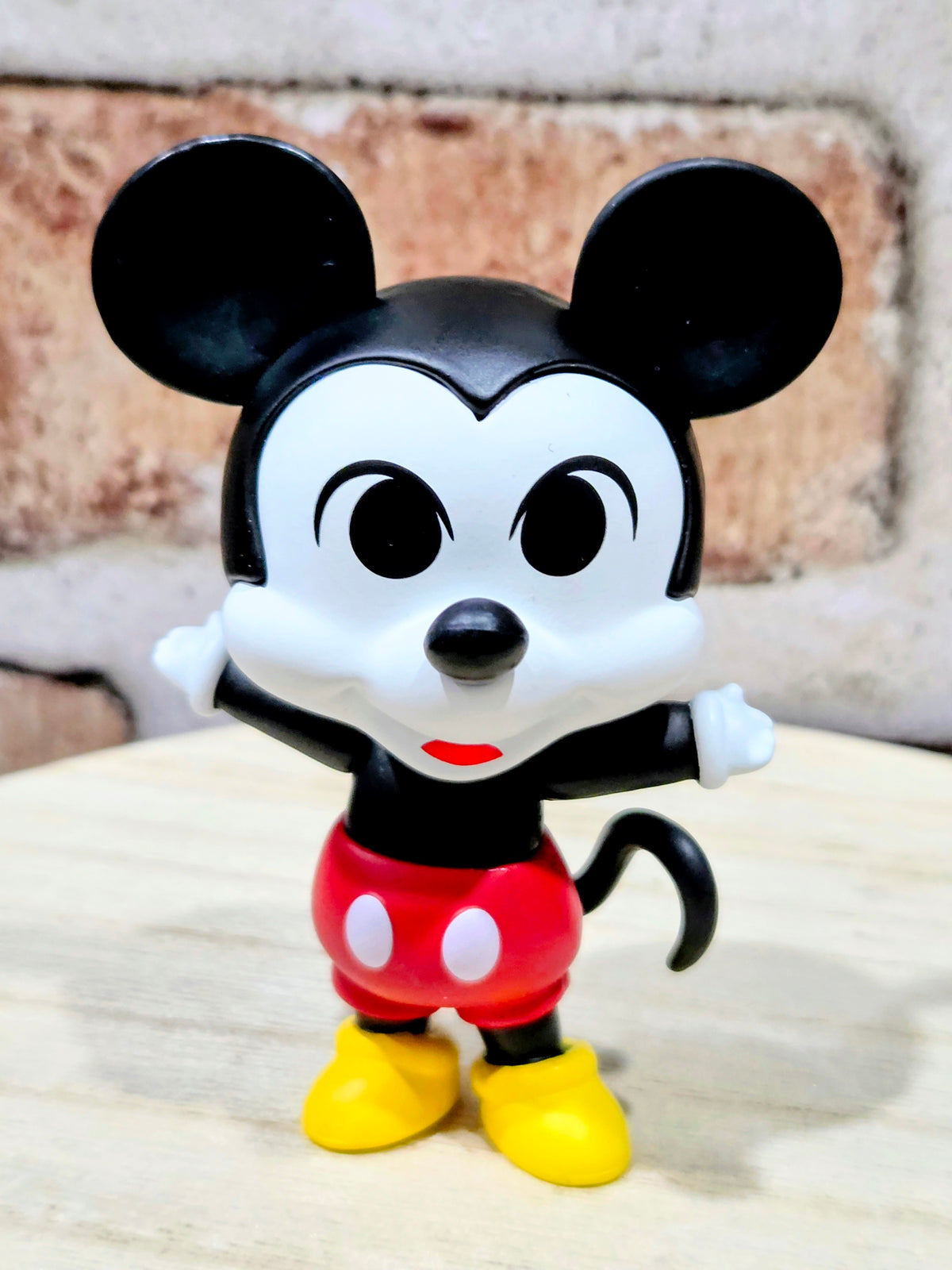 Mickey Mouse vinyl figure with red shorts and yellow shoes, front view.