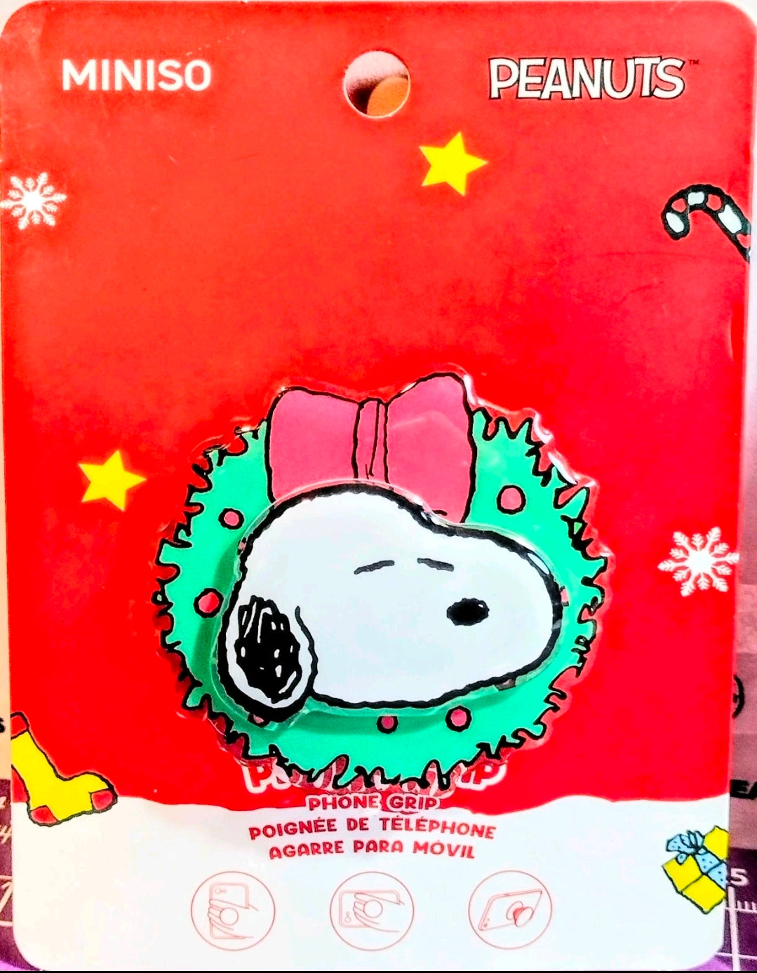 Red MINISO PEANUTS blister card featuring Snoopy phone grip with star and snowflake icons.