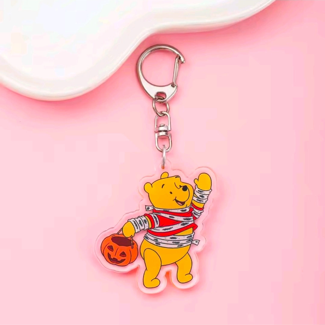 Acrylic Halloween keychain with carabiner; yellow Winnie the Pooh in striped bandage outfit holding a jack-o-lantern.