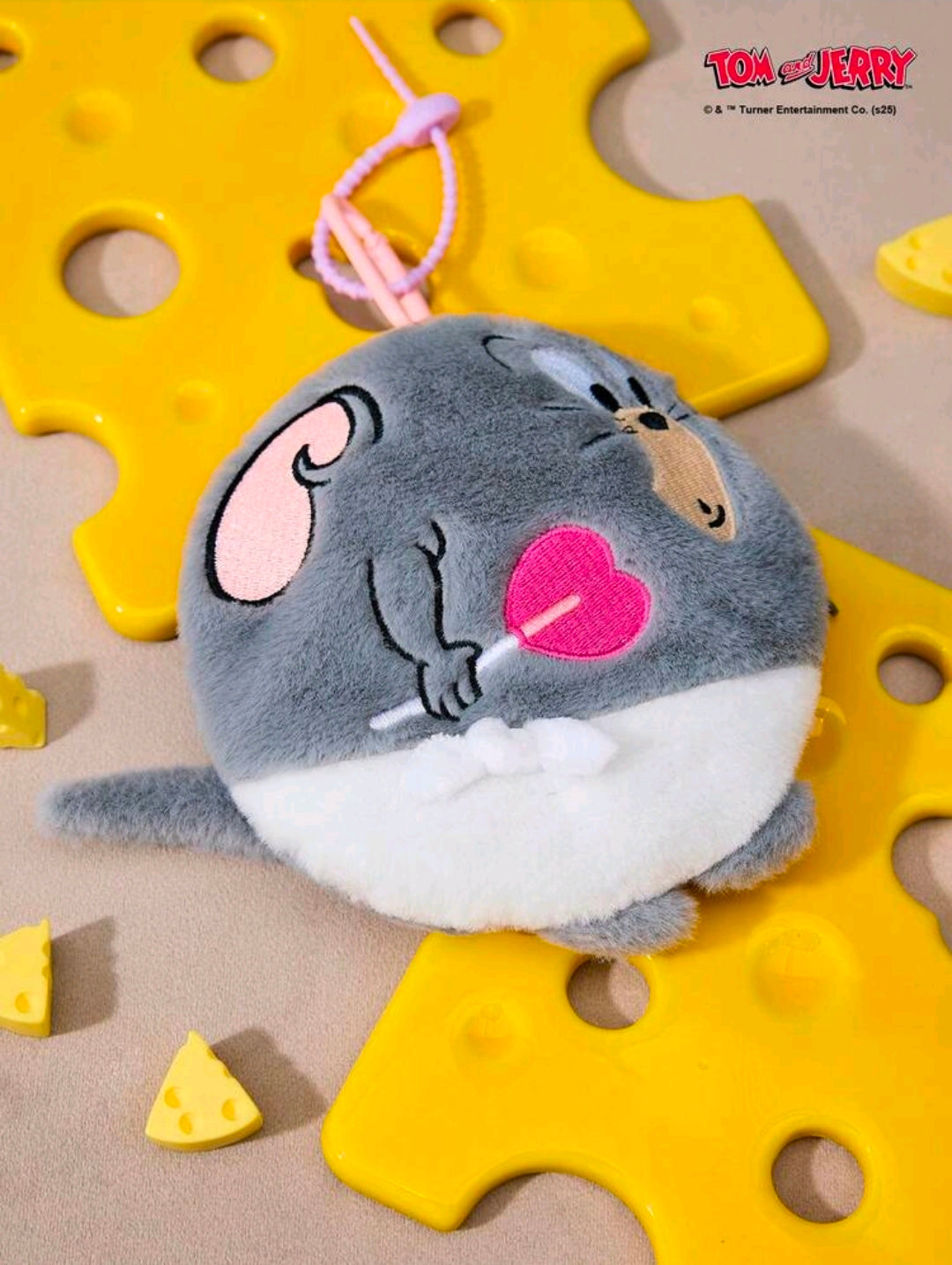 Grey round plush keychain bag charm with pink heart, near yellow cheese shapes
