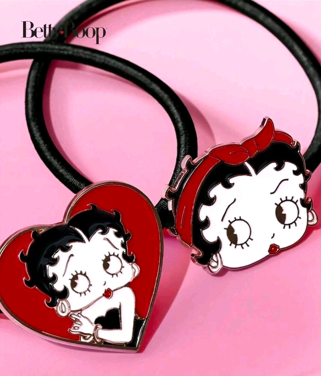 Pair of hair ties with black bands and red heart charms featuring cartoon faces