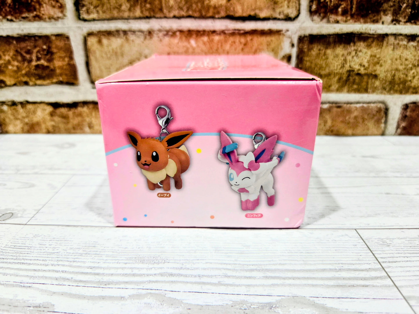 Pink keychain blind box side panel with Eevee and light-gray fairy character charm