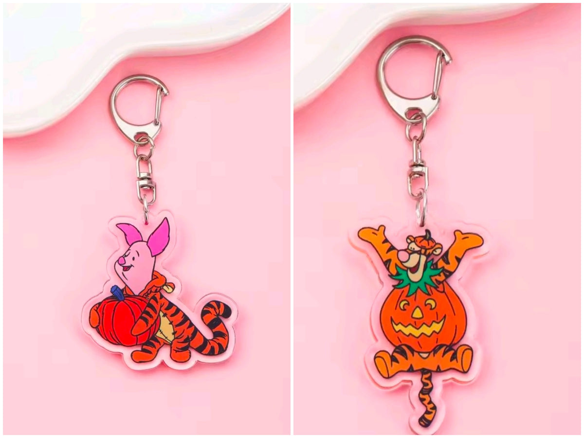 Acrylic Halloween keychain with carabiner; tiger-like character in jack-o-lantern costume with green accents.