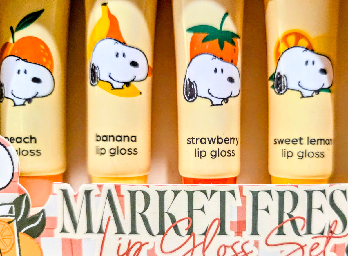 Four fruit lip gloss tubes: peach, banana, strawberry, sweet lemon, inside a display