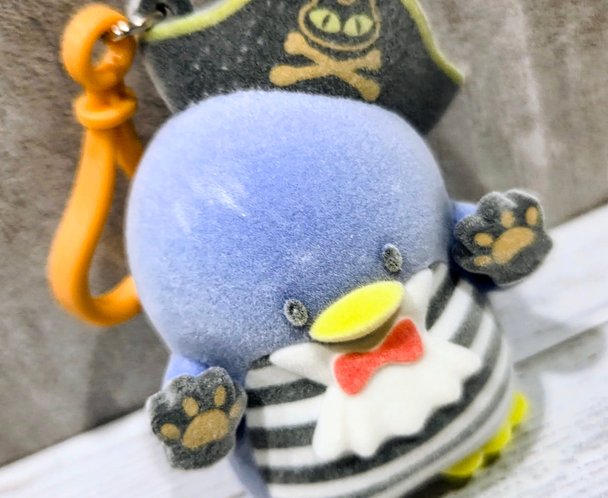 Close-up of blue Tuxedo Sam plush bag clip with pirate hat and striped outfit