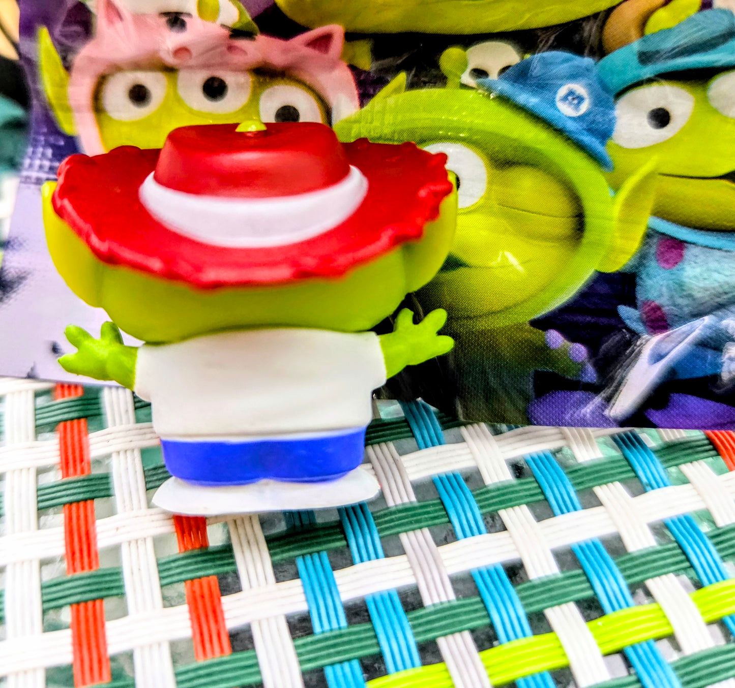 Green alien mini figure wearing red pizza-slice hat, white shirt, and blue shorts