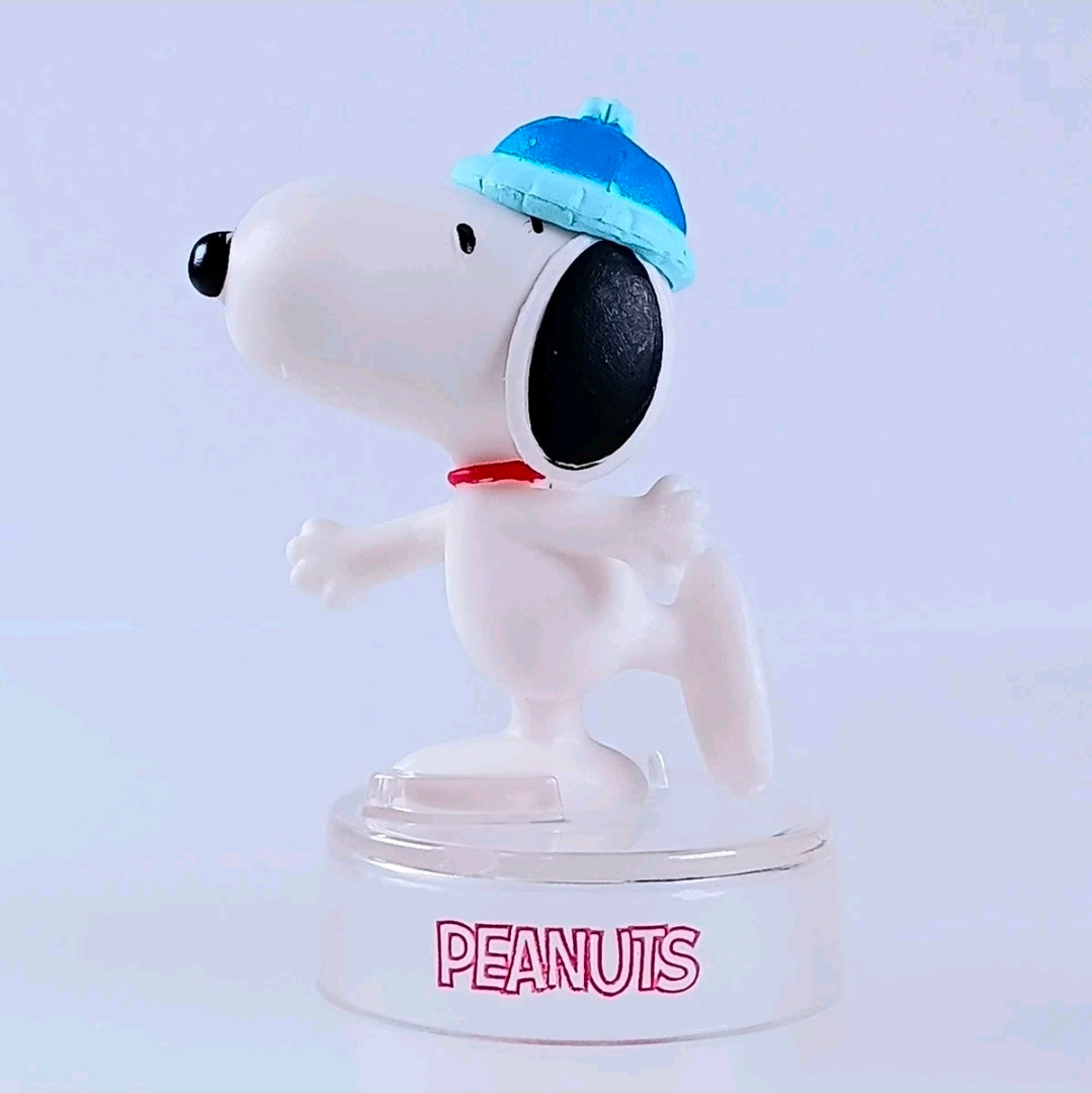 Snoopy figure in white with a light blue hat, red collar, and clear display base