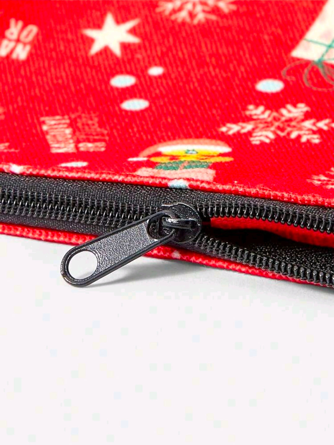 Red holiday makeup bag zipper close-up with black metal pull tab and teeth
