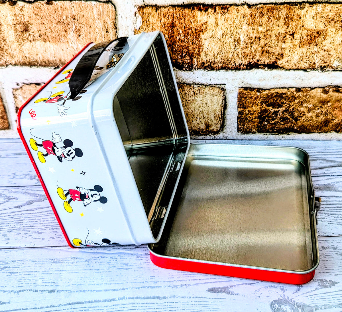 Opened rectangular snack tin with Mickey graphics on the lid and sides
