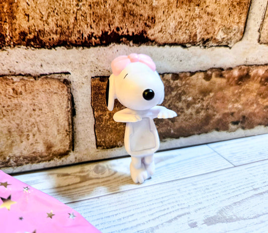 White mini figure with pink bow and black eyes, standing pose