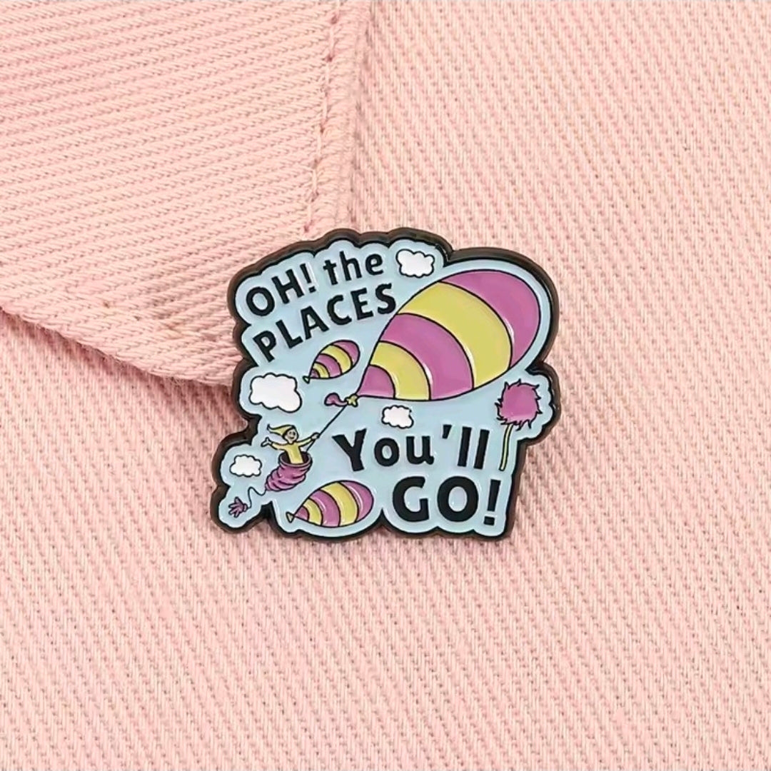 Oh the Places You'll Go! enamel pin on pink textured fabric.