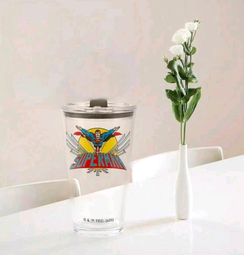 Clear tumbler mug with black lid and Superman emblem, front view.