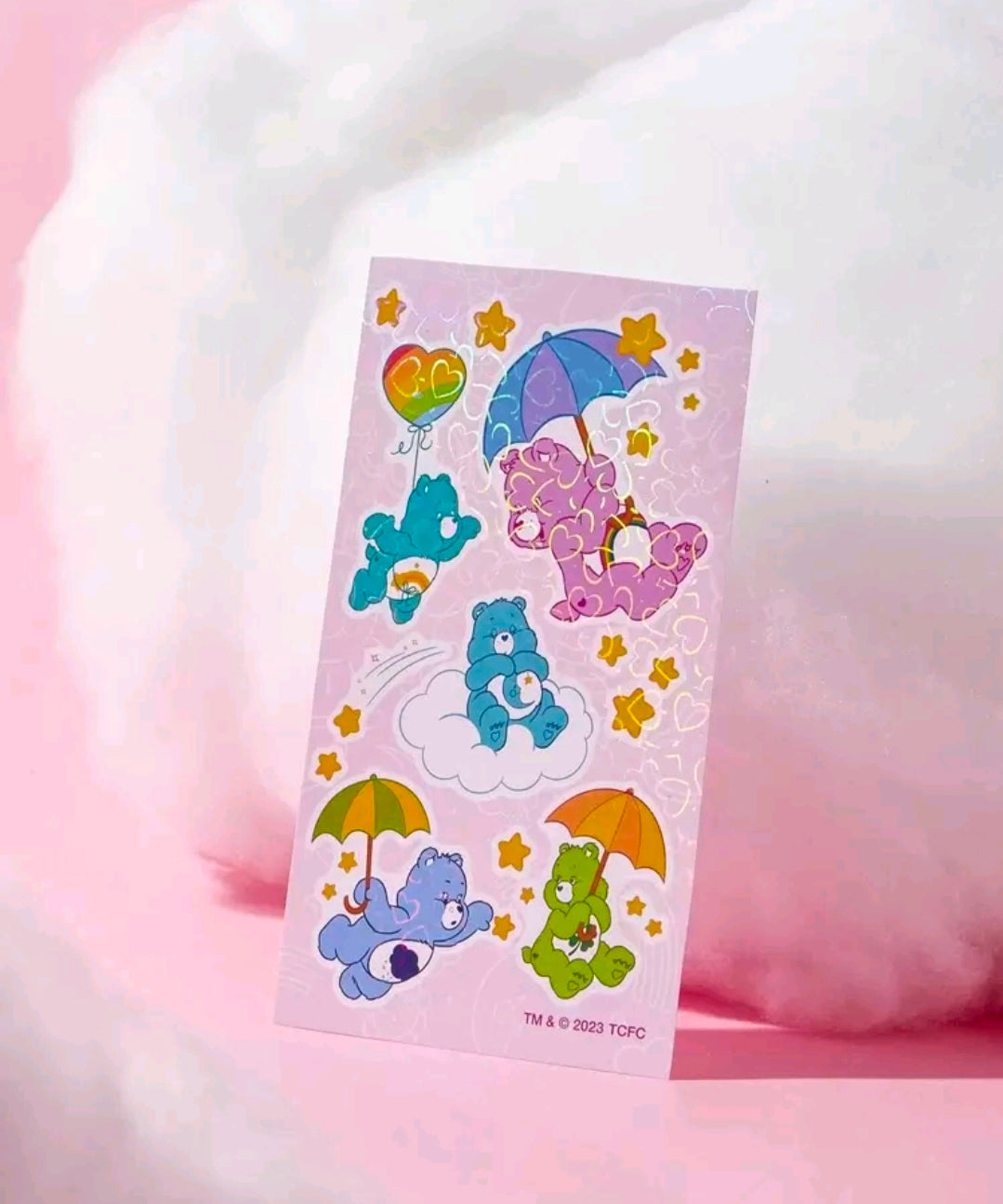 Holographic sticker sheet with Care Bears under an umbrella, stars, and pastel hearts