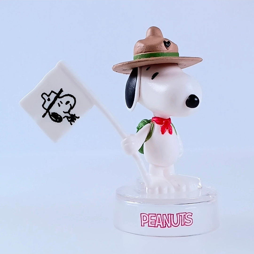 Snoopy figure in brown hat holding white sign with black Snoopy outline, clear base