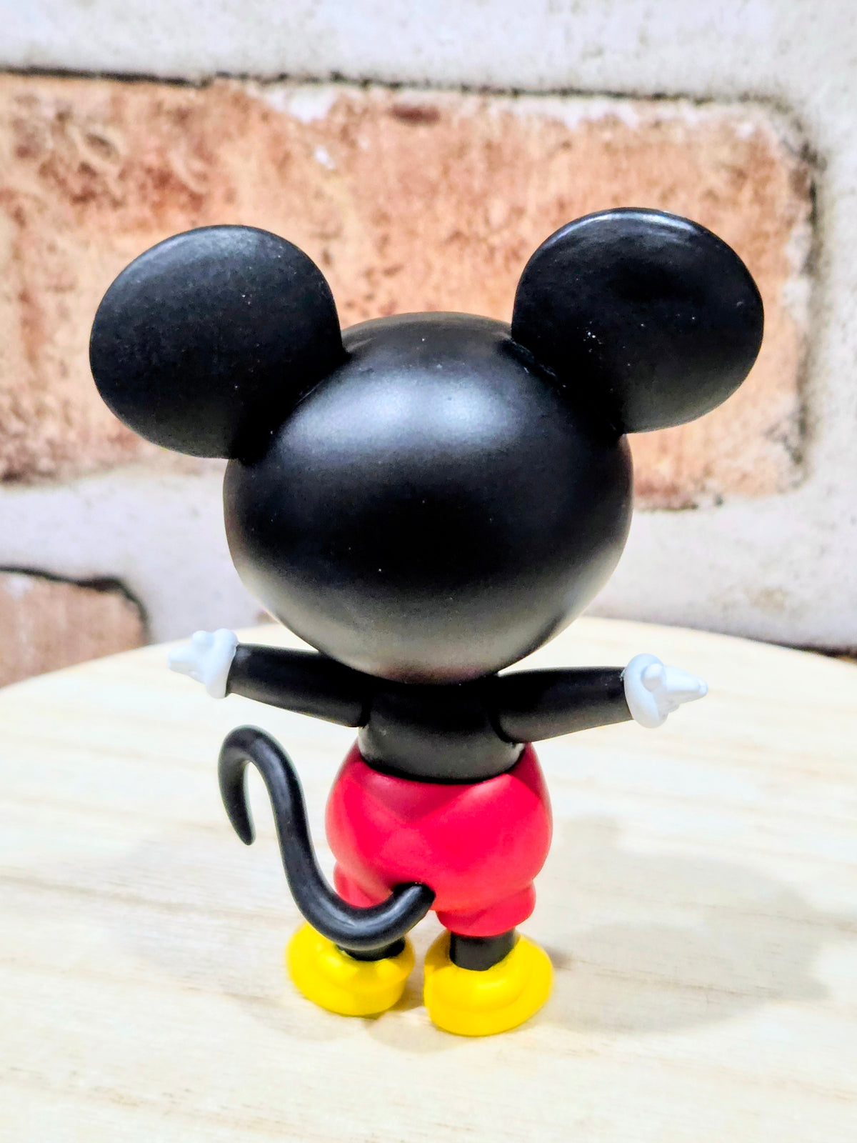 Mickey Mouse vinyl figure, back view with red pants and yellow shoes.
