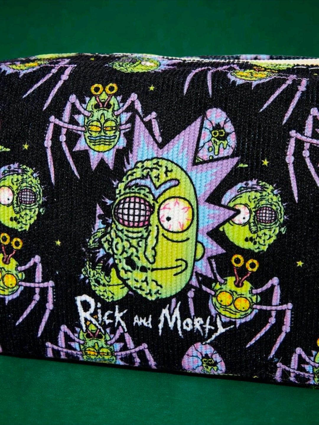 Close-up of black makeup bag with repeating green-and-purple sci-fi character graphics.