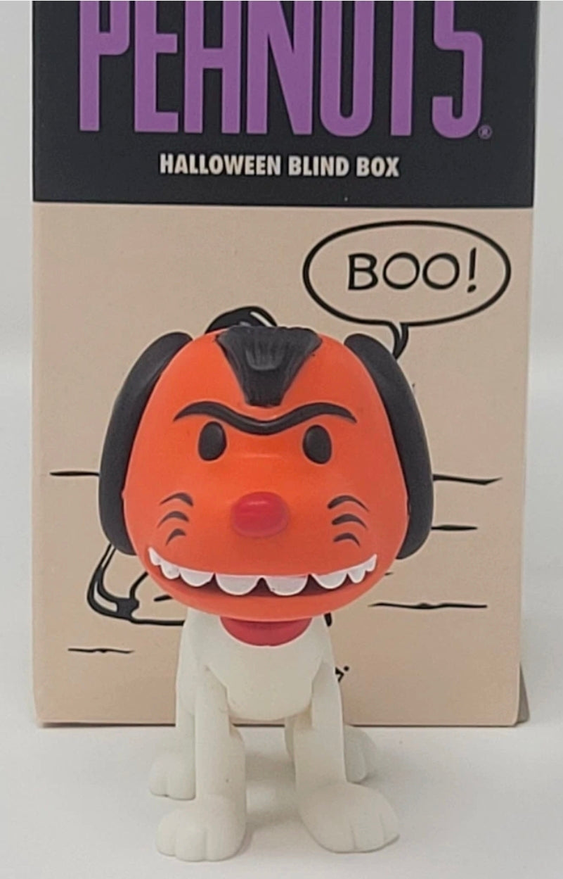 Orange-masked dog Halloween blind box figure standing in front of tan cardboard packaging
