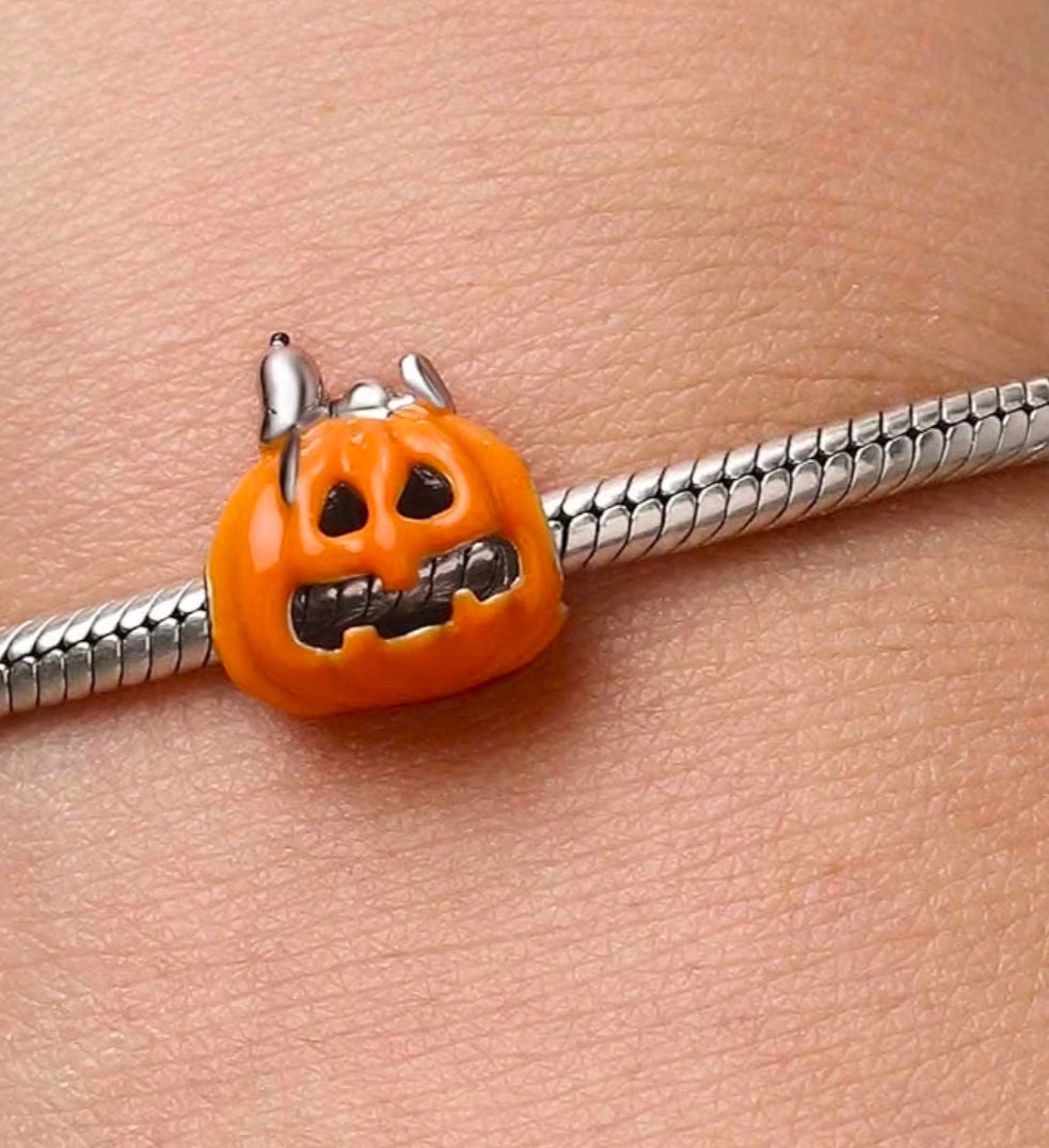 Jack-o'-lantern orange enamel charm on a silver bracelet chain with small dog figure