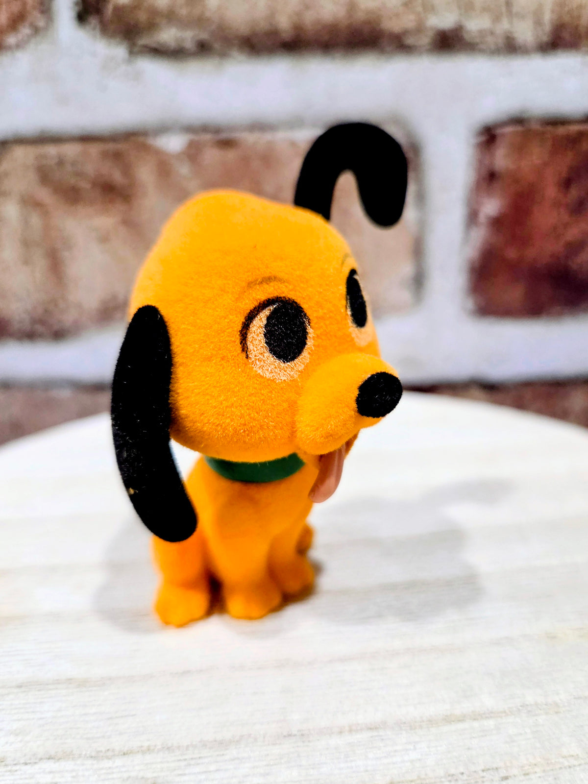 Flocked Pluto mini figure close-up, orange plush face with black nose and ears
