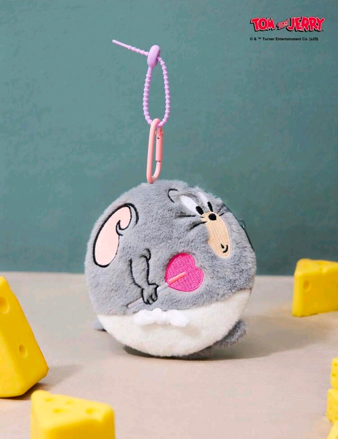 Grey round plush keychain bag charm hanging on pink cord loop, pink heart