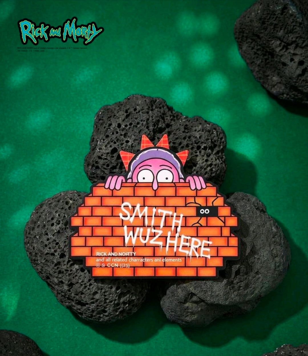 Brick-style die-cut sticky note on dark rocks with character behind