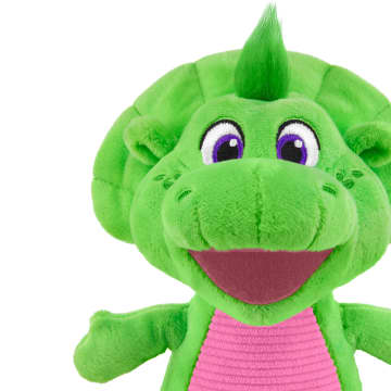Green plush dinosaur character with purple-lined eyes and pink striped shirt, smiling