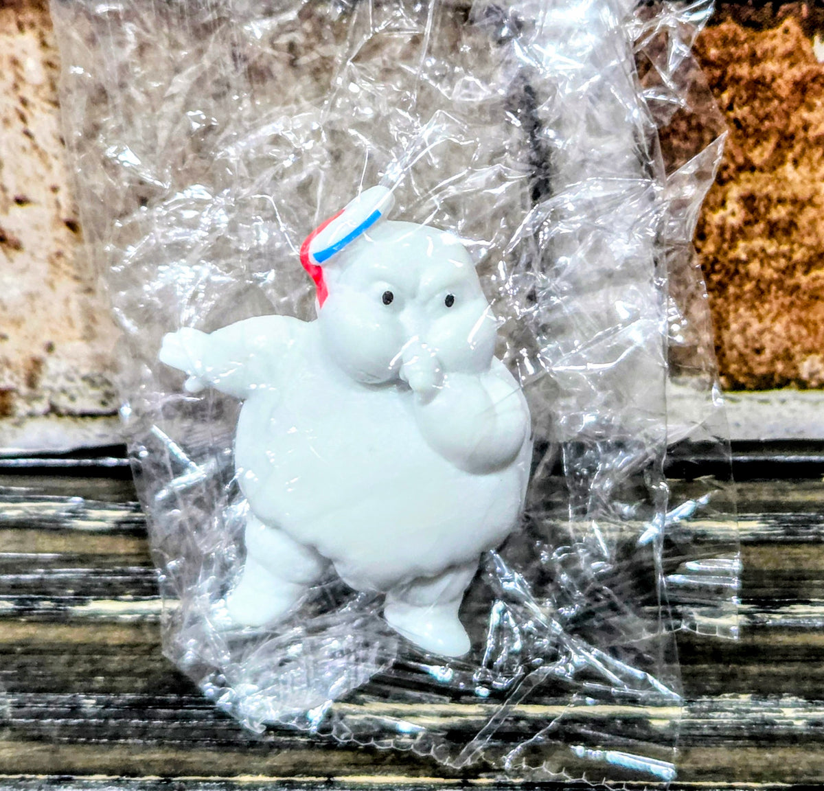 White mini Puft figure holding its hands up, red-and-blue striped hat.