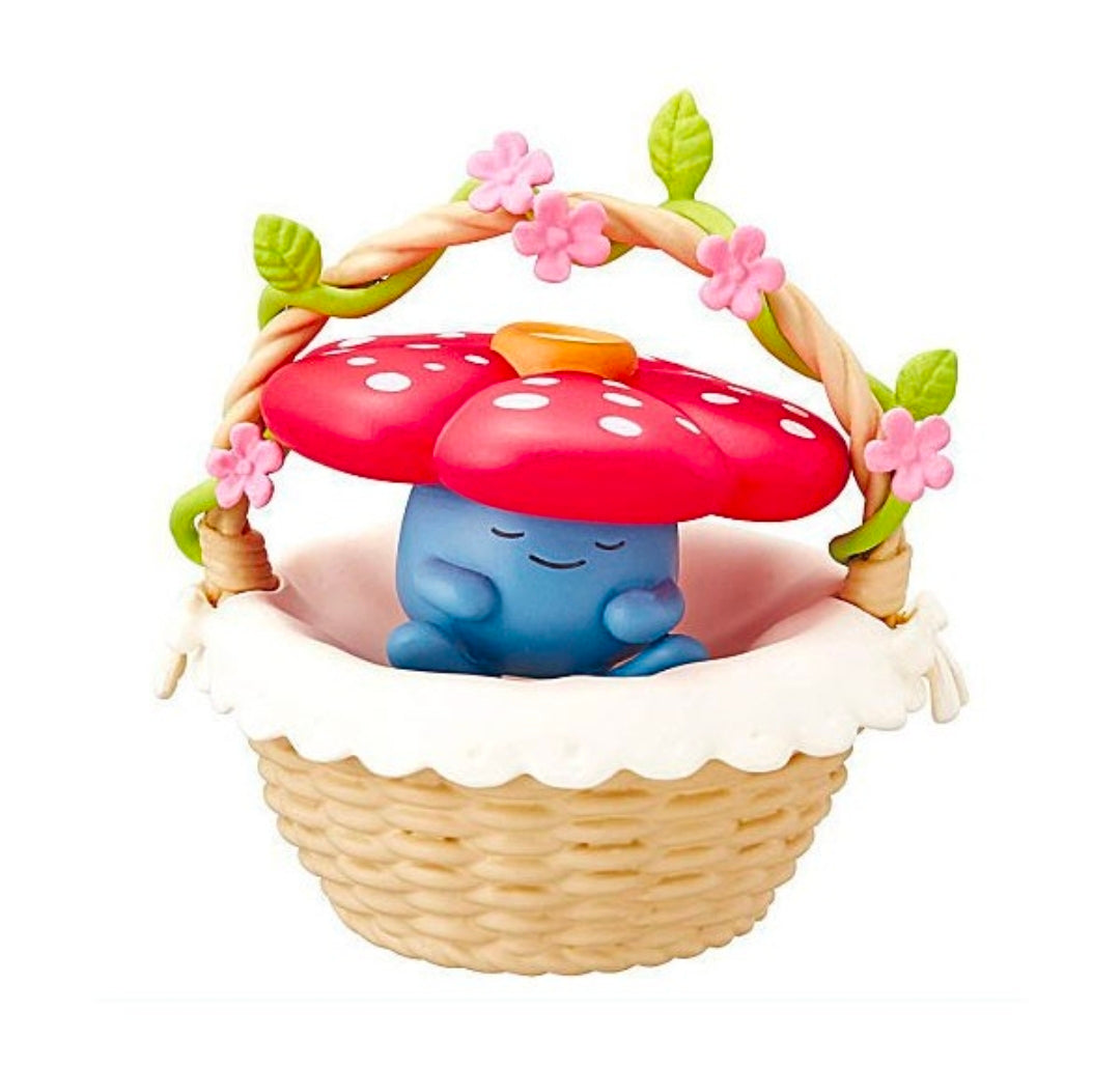 Miniature blue sleeping character in red mushroom basket with pink blossoms and green leaves