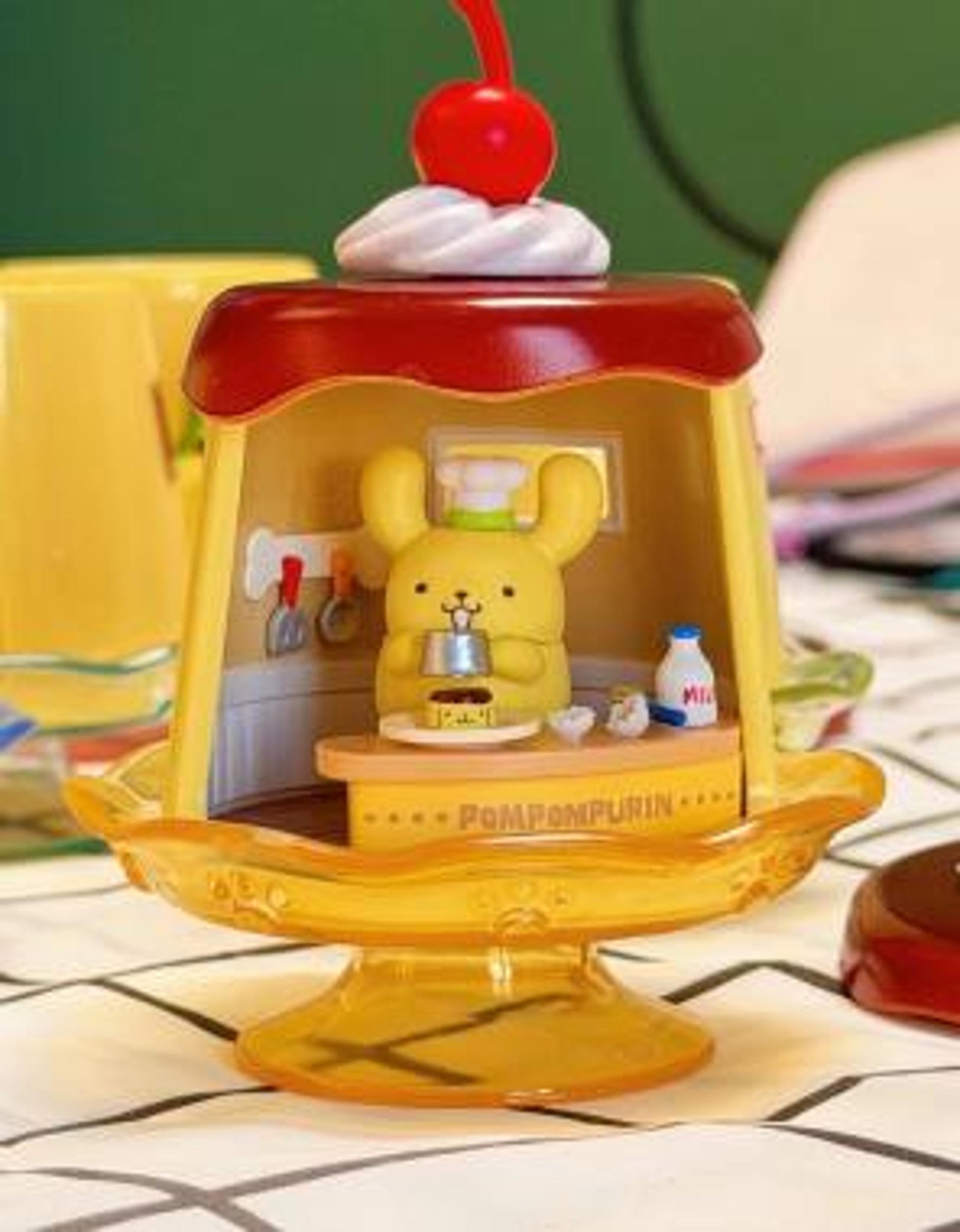 Pompompurin mini figure close-up in kitchen dome, chef items and small toys