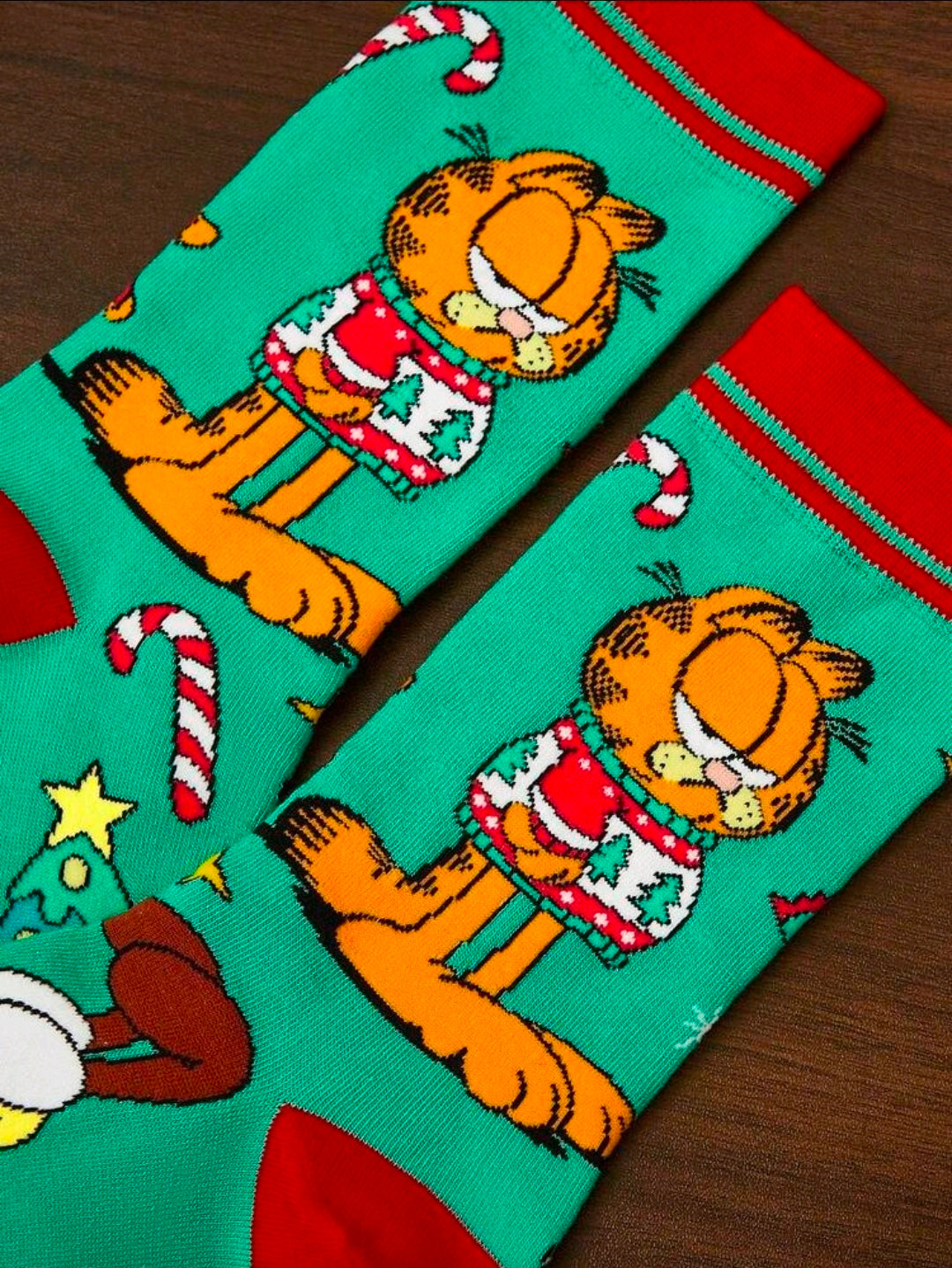Close-up of teal Garfield crew socks with candy-cane and Christmas tree graphics