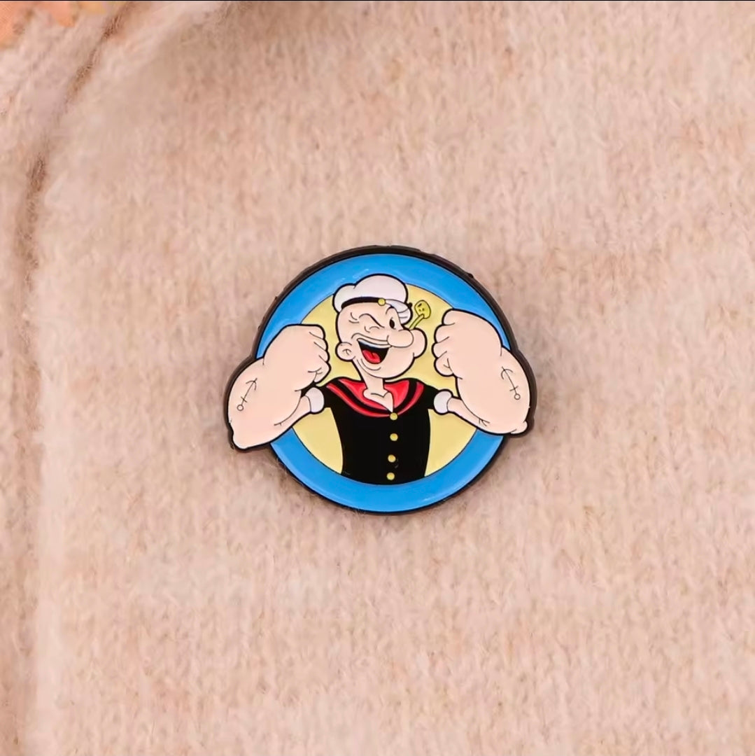 Cartoon sailor face enamel lapel pin, blue circular design with flexed fists.