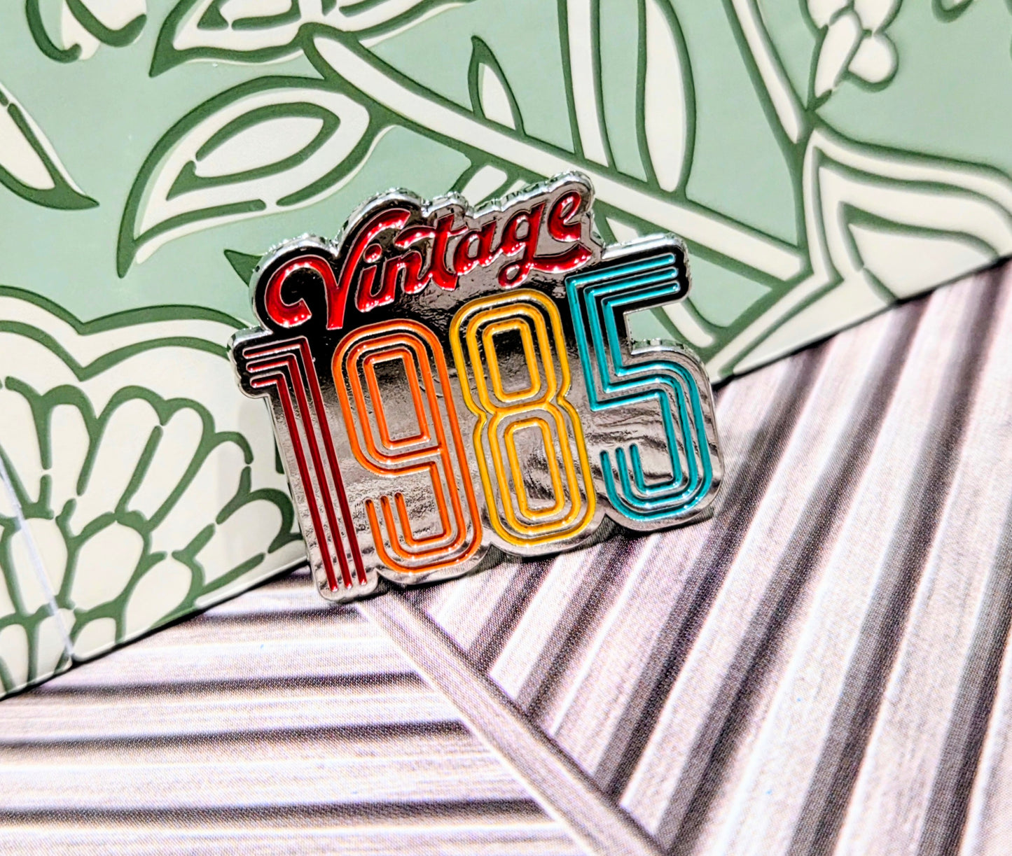 Enamel pin with 'Vintage 1985' rainbow striped lettering