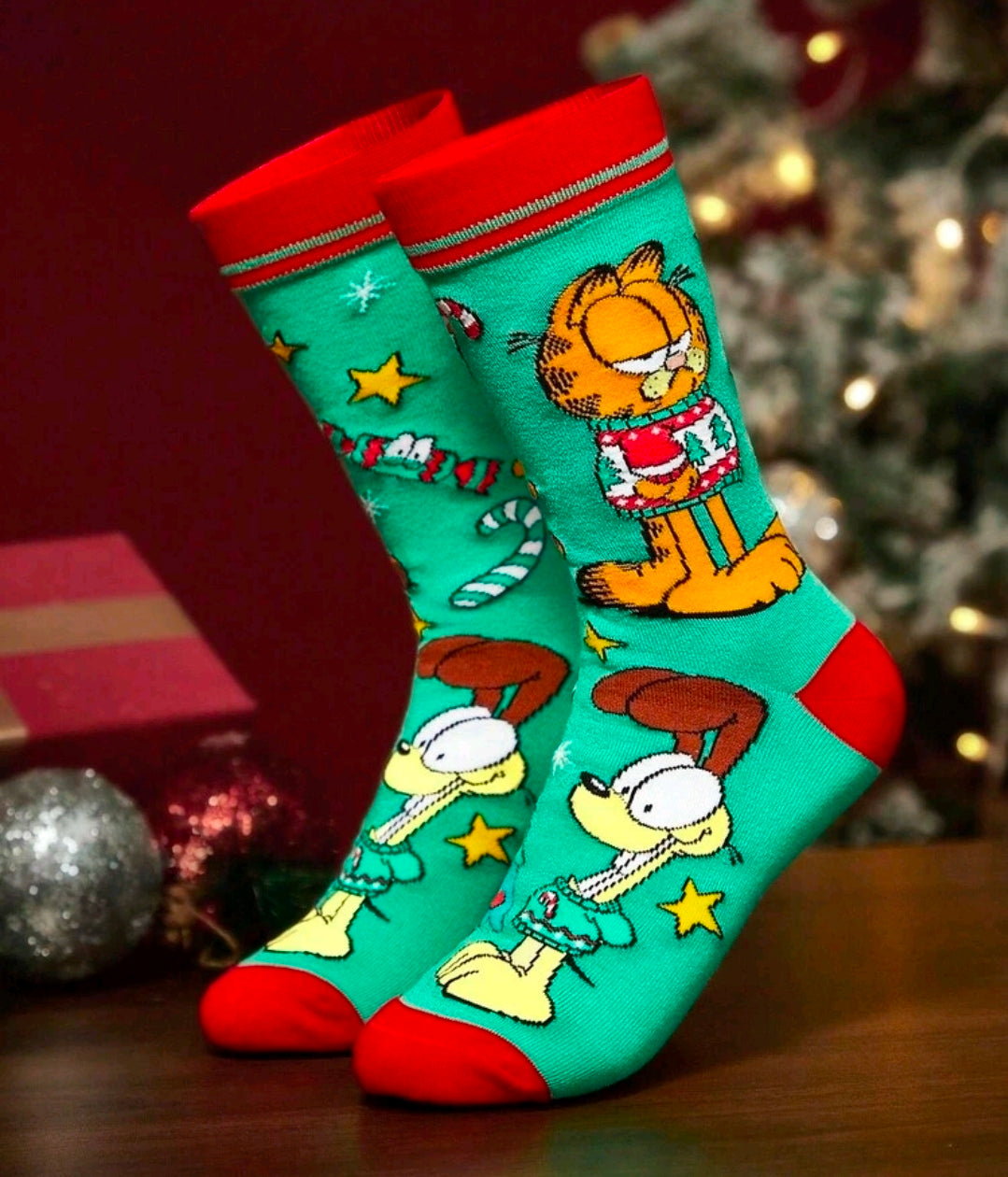 Pair of teal Garfield holiday crew socks with red heels and festive character prints