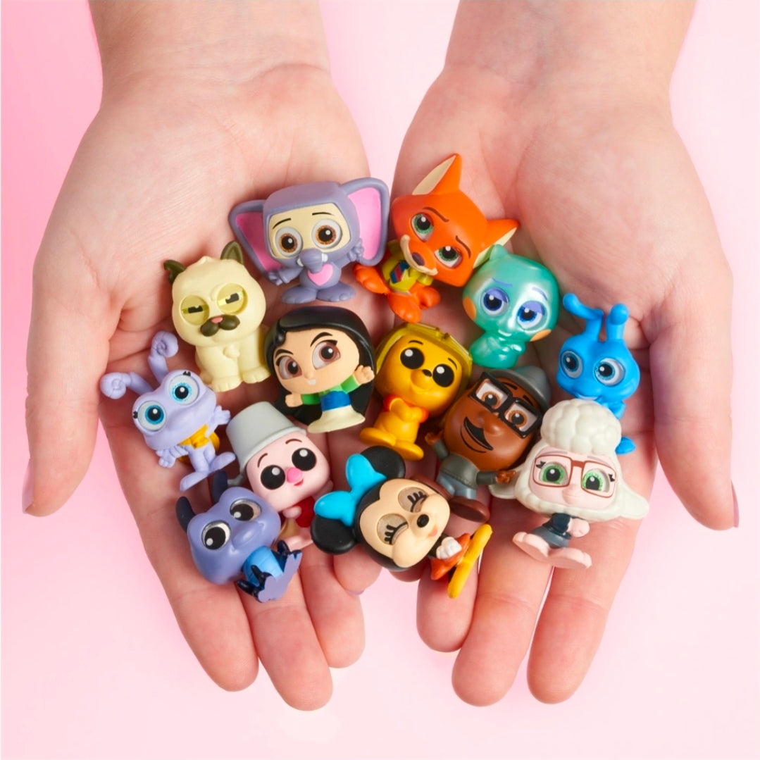 Set of small character collectible figures in assorted colors, held in two hands