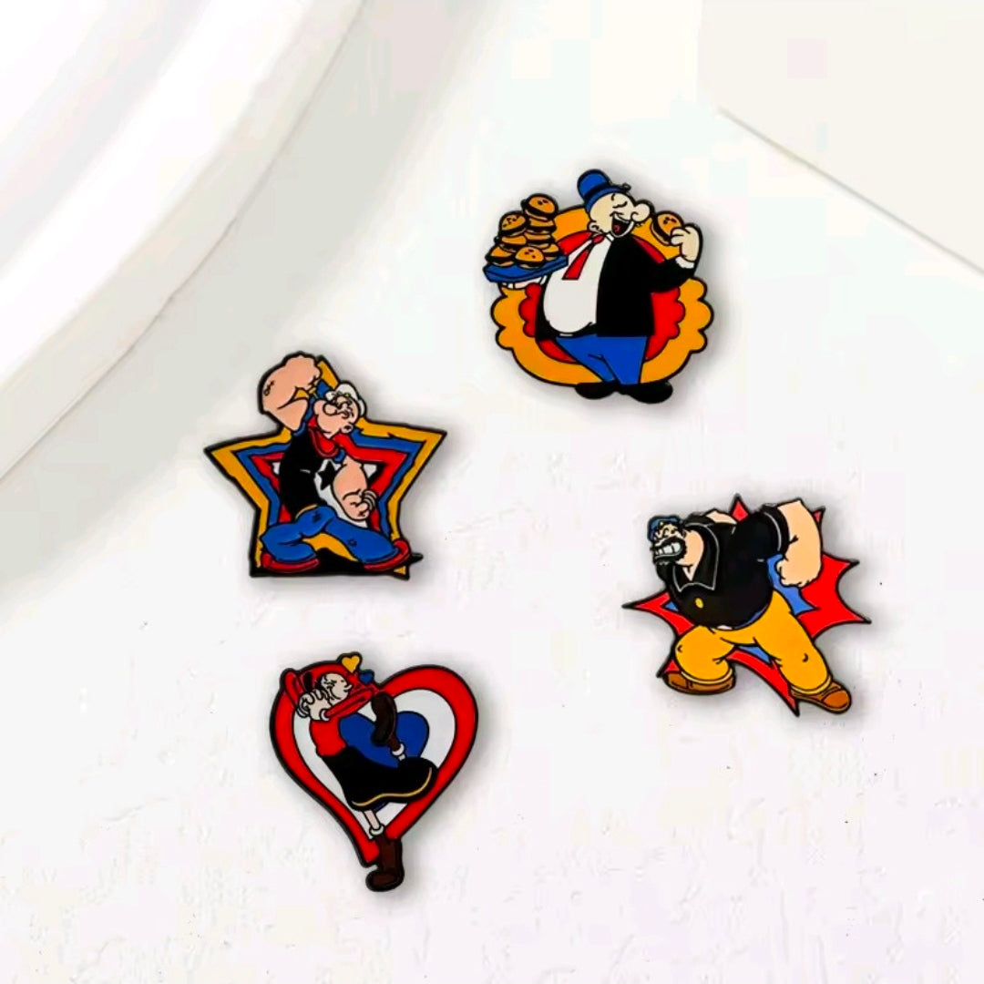 Four cartoon enamel lapel pins scattered on a white surface: Popeye, Brutus, Olive Oyl, Wimpy.