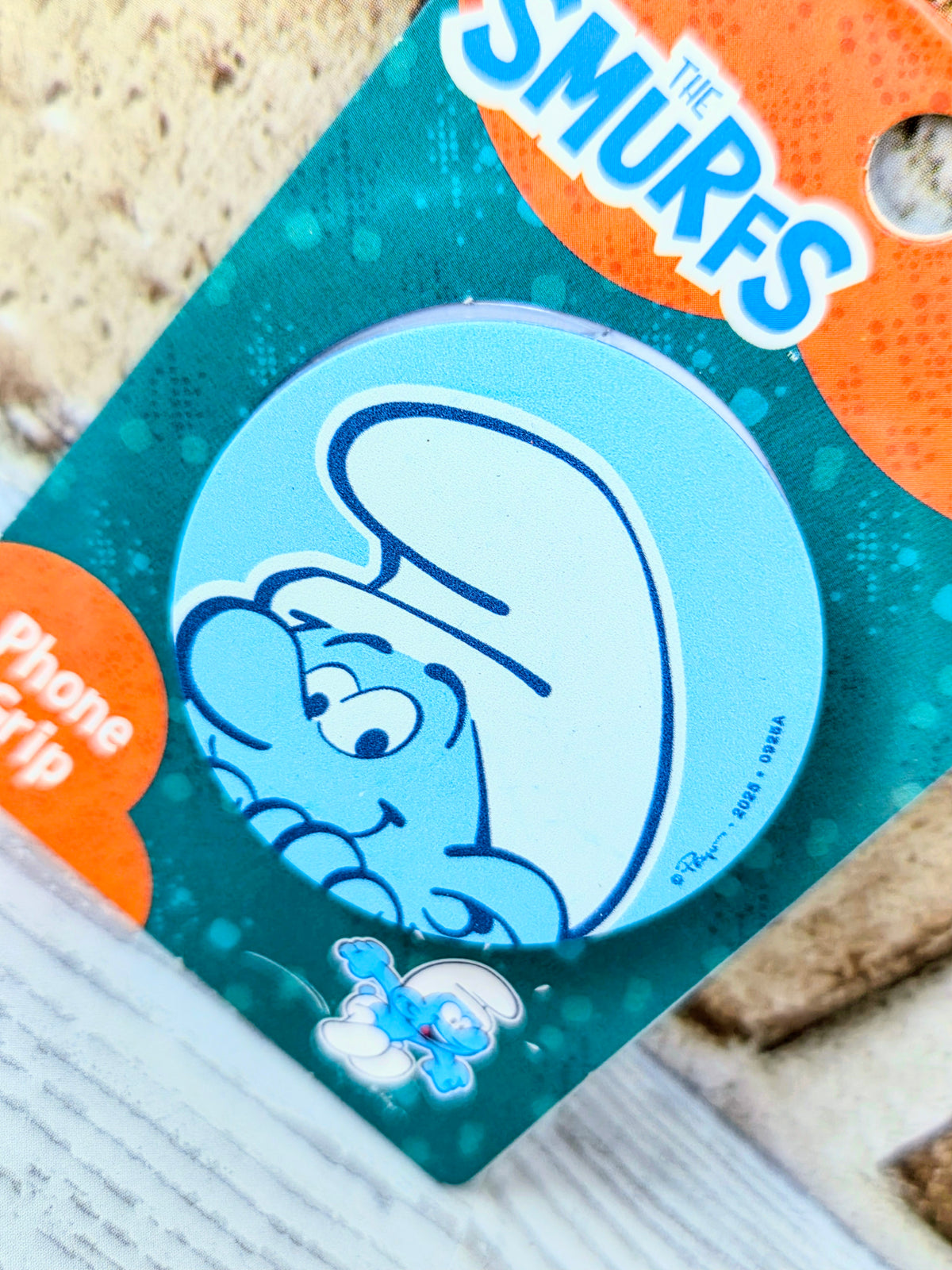 Teal phone grip accessory card with blue circular chef character graphic