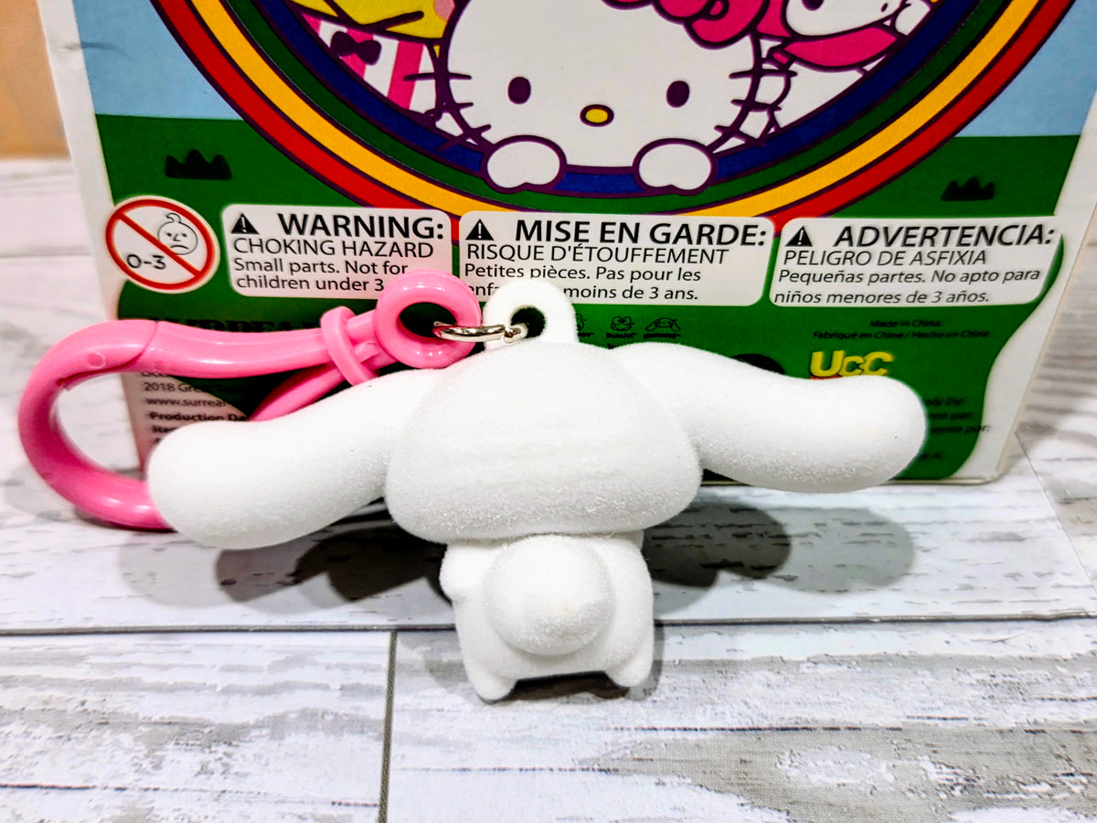 White flocked character keychain with pink ring, angled front view on box backing.