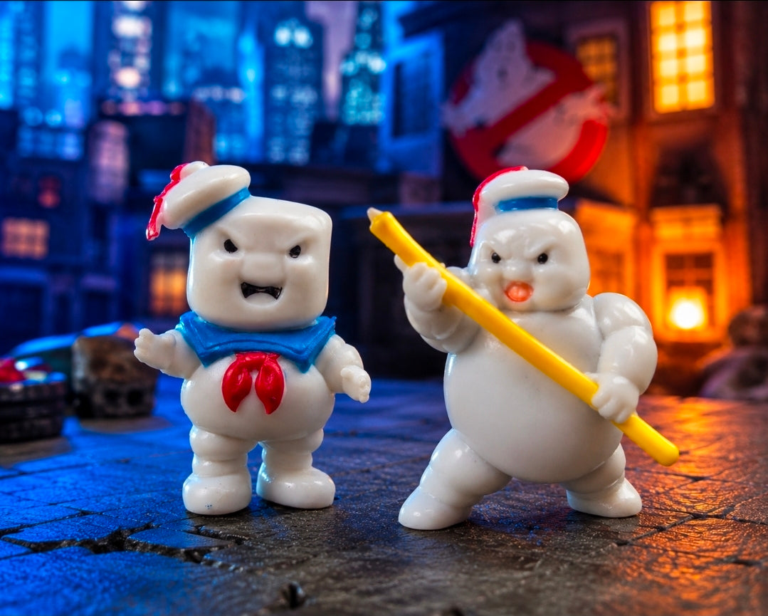 Pair of white Mini-Puft figures with red accents; one holds a yellow ray gun, both stand