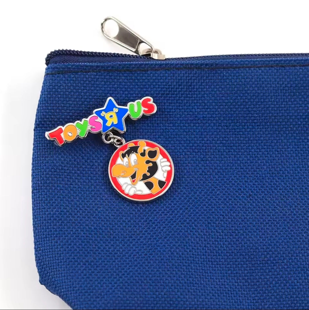 Enamel dangle charm pin attached to blue fabric pouch