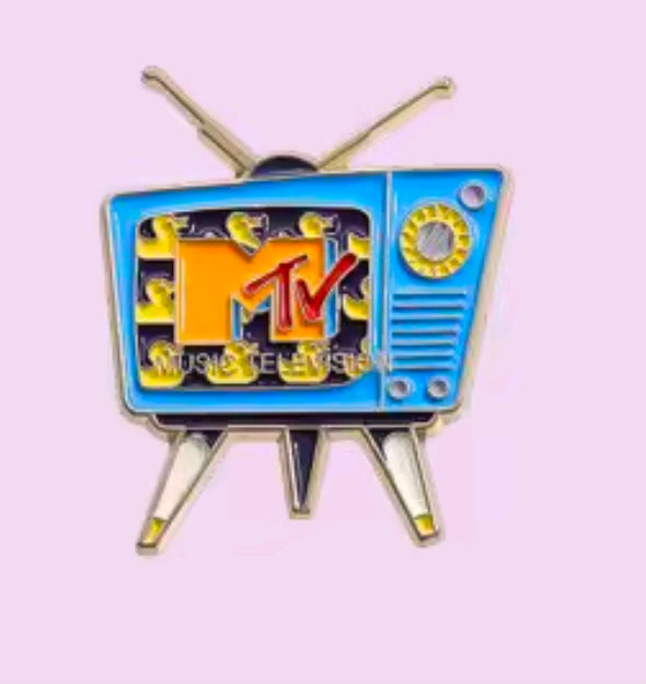 Close-up of retro TV enamel pin with blue, orange, and yellow artwork and gold antenna posts