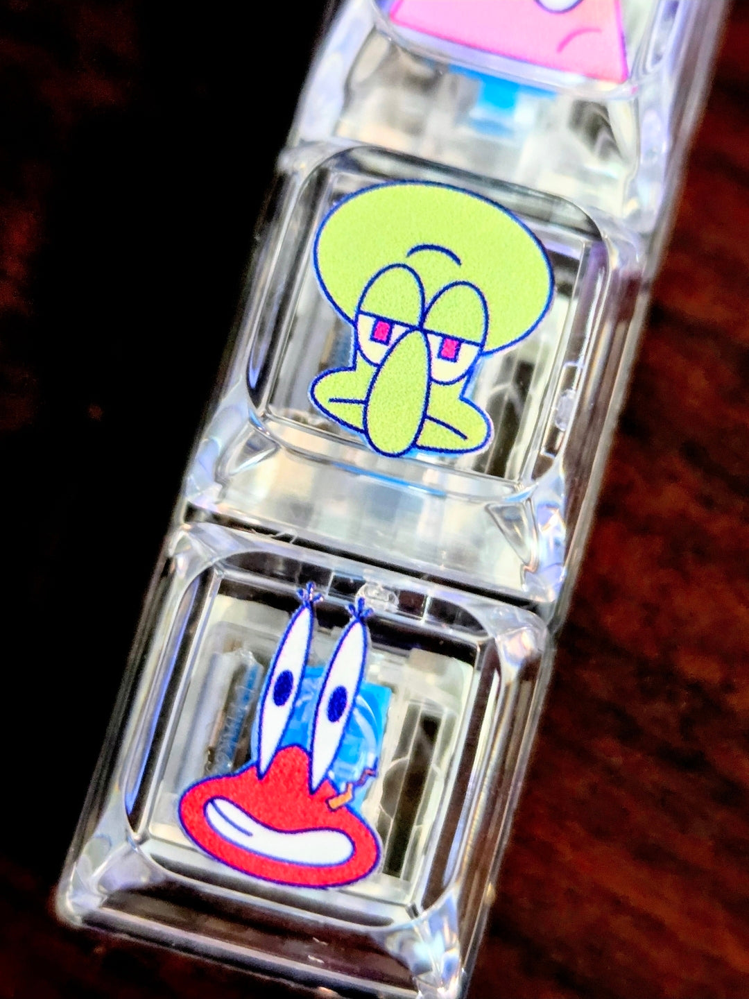 Clear acrylic keyboard fidget keychain close-up with green and blue/red character faces