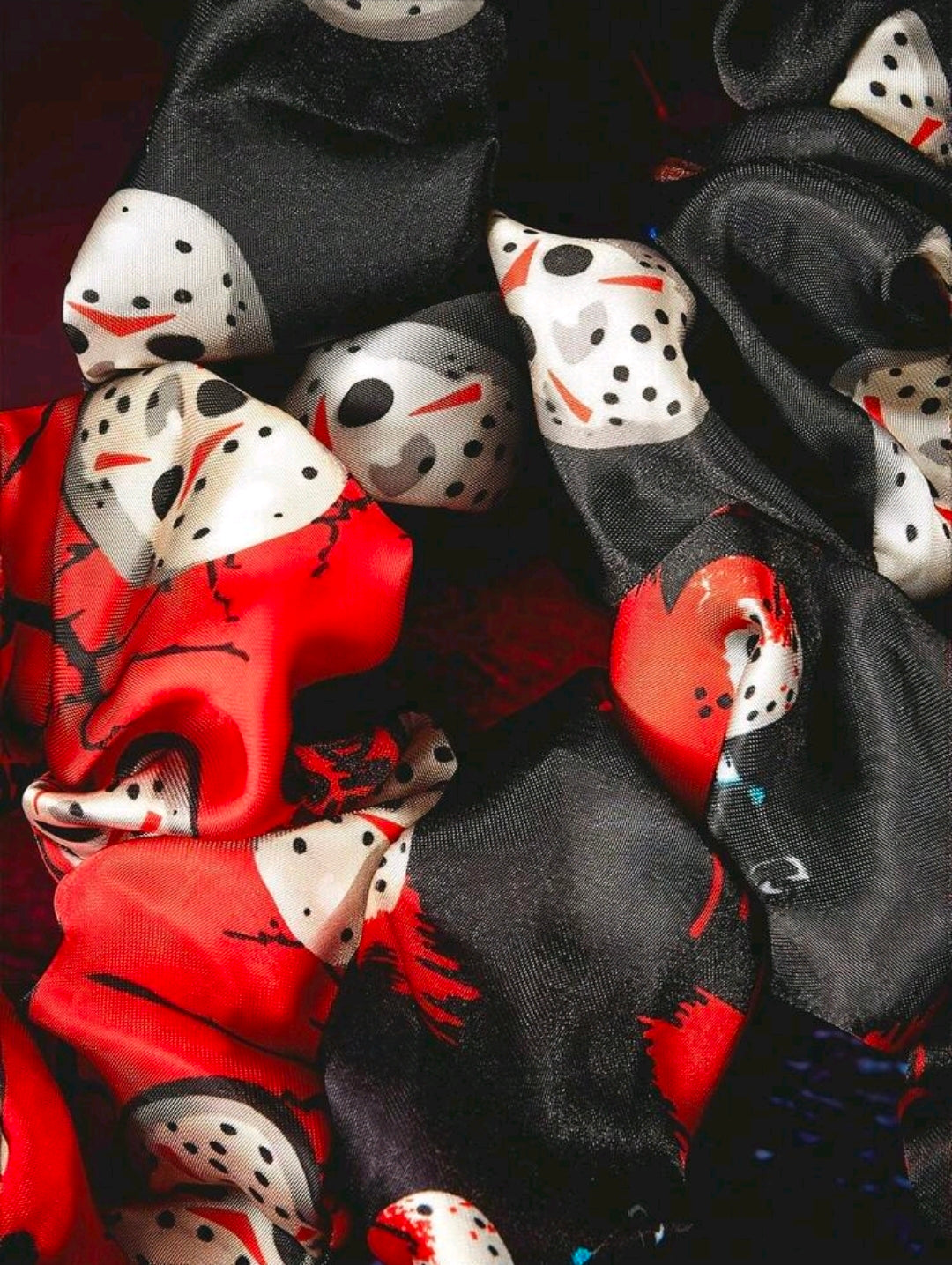 Assorted scrunchies with black-and-red fabric and Jason-style hockey mask graphics