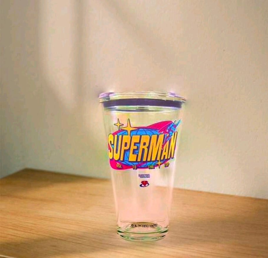 Clear Superman glass tumbler with black lid on table