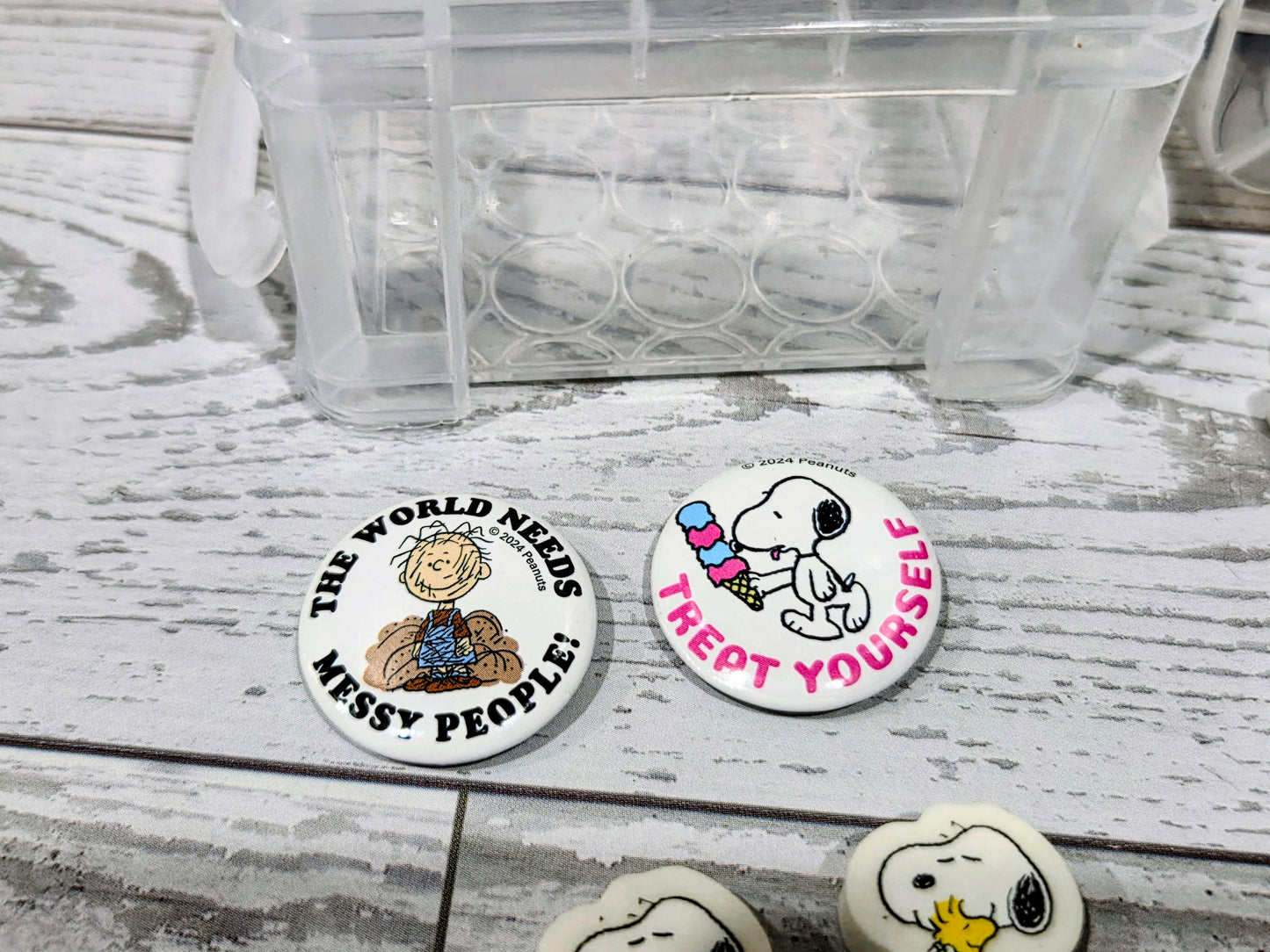 Round Snoopy character erasers with colorful text graphics beside clear organizer box