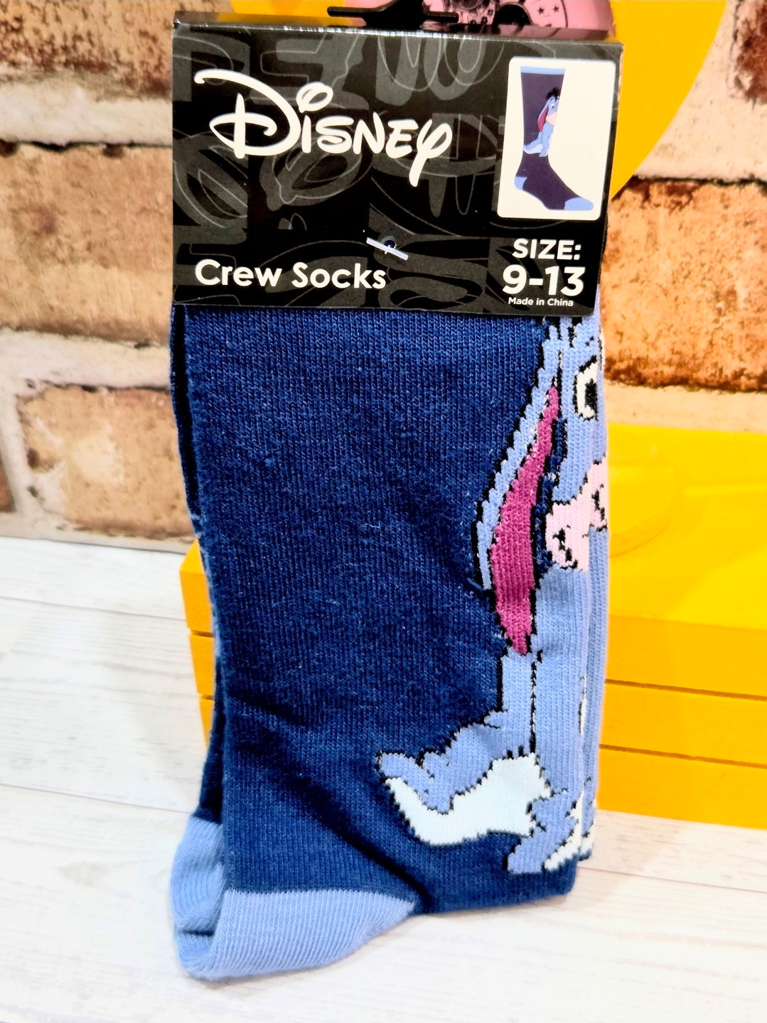 Packaged blue crew socks with Eeyore character graphic, visible toe and cuff